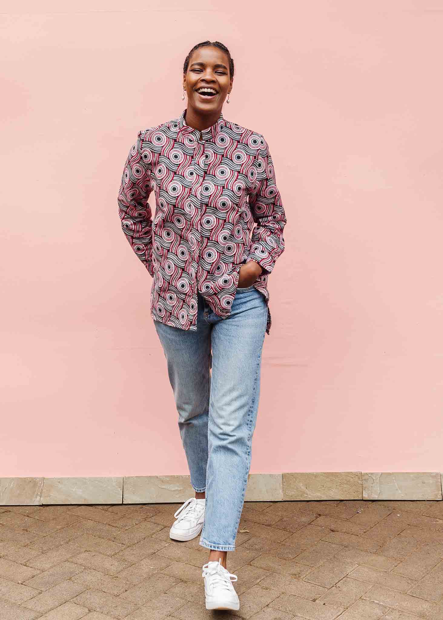 Model wearing long sleeve blouse with black, red, and white circles.