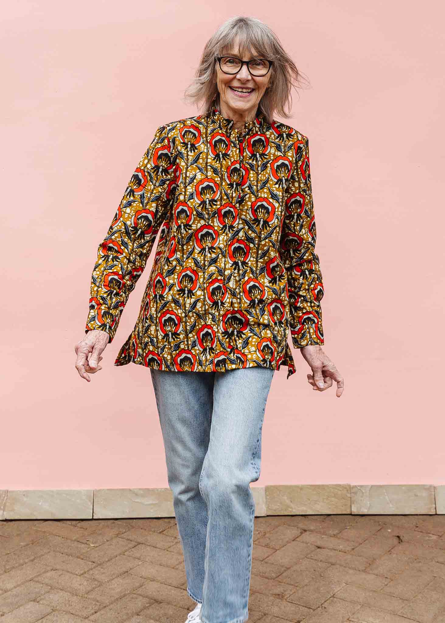 Model wearing mustard long sleeve blouse with red floral print.