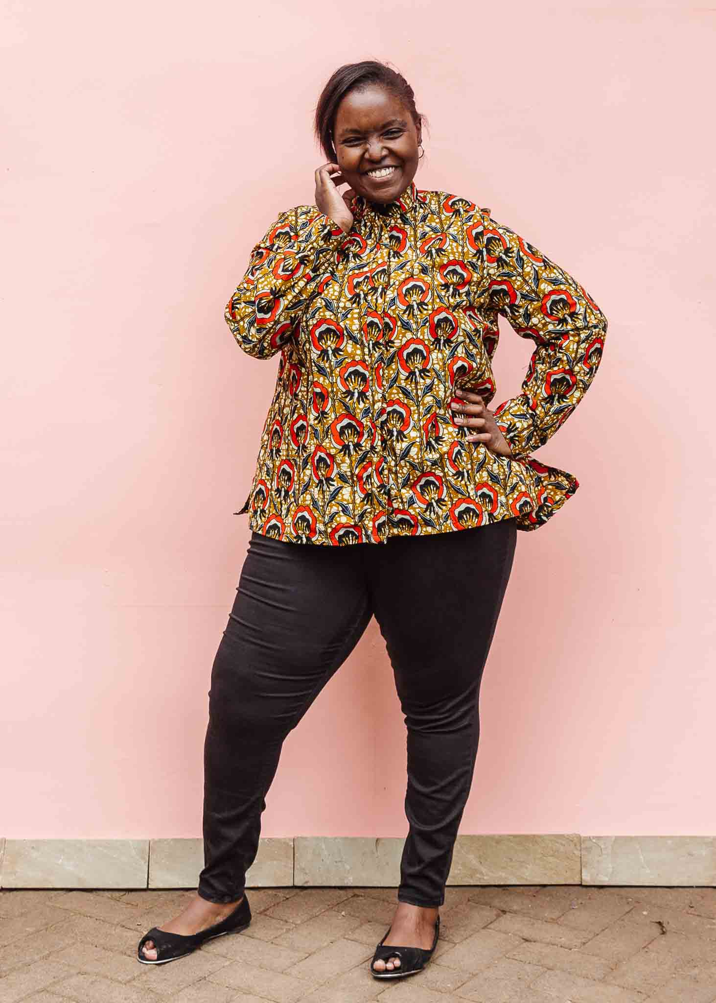 Model wearing mustard long sleeve blouse with red floral print.