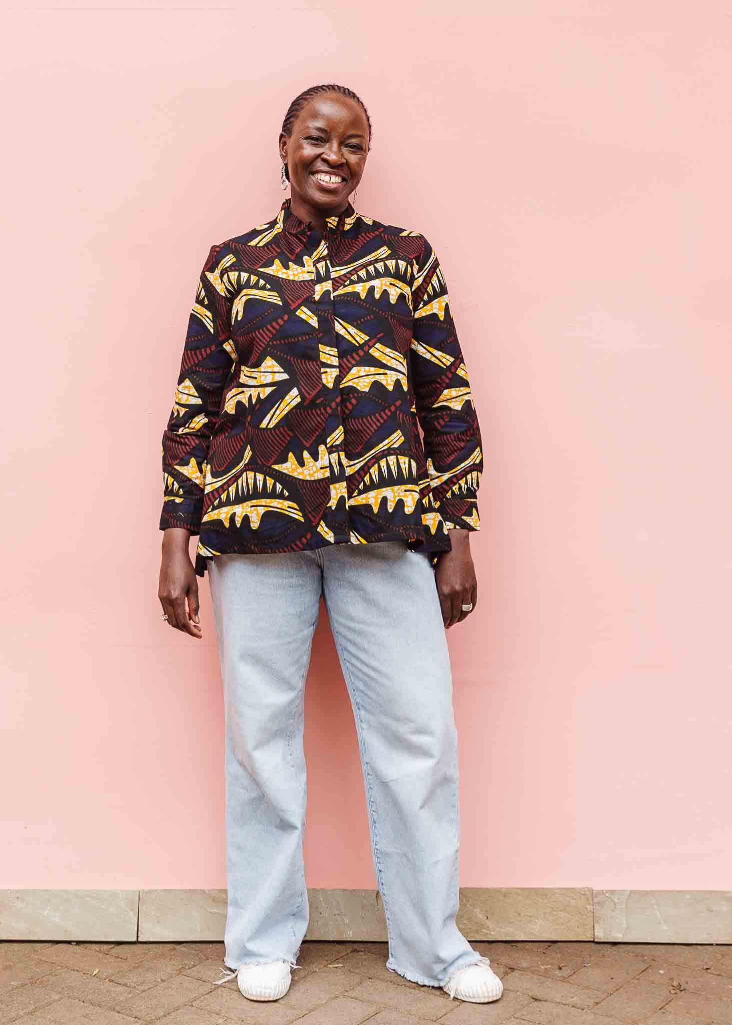 Model wearing long sleeve blouse with brown and yellow abstract print.