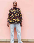 Model wearing long sleeve blouse with brown and yellow abstract print.