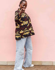 Model wearing long sleeve blouse with brown and yellow abstract print.