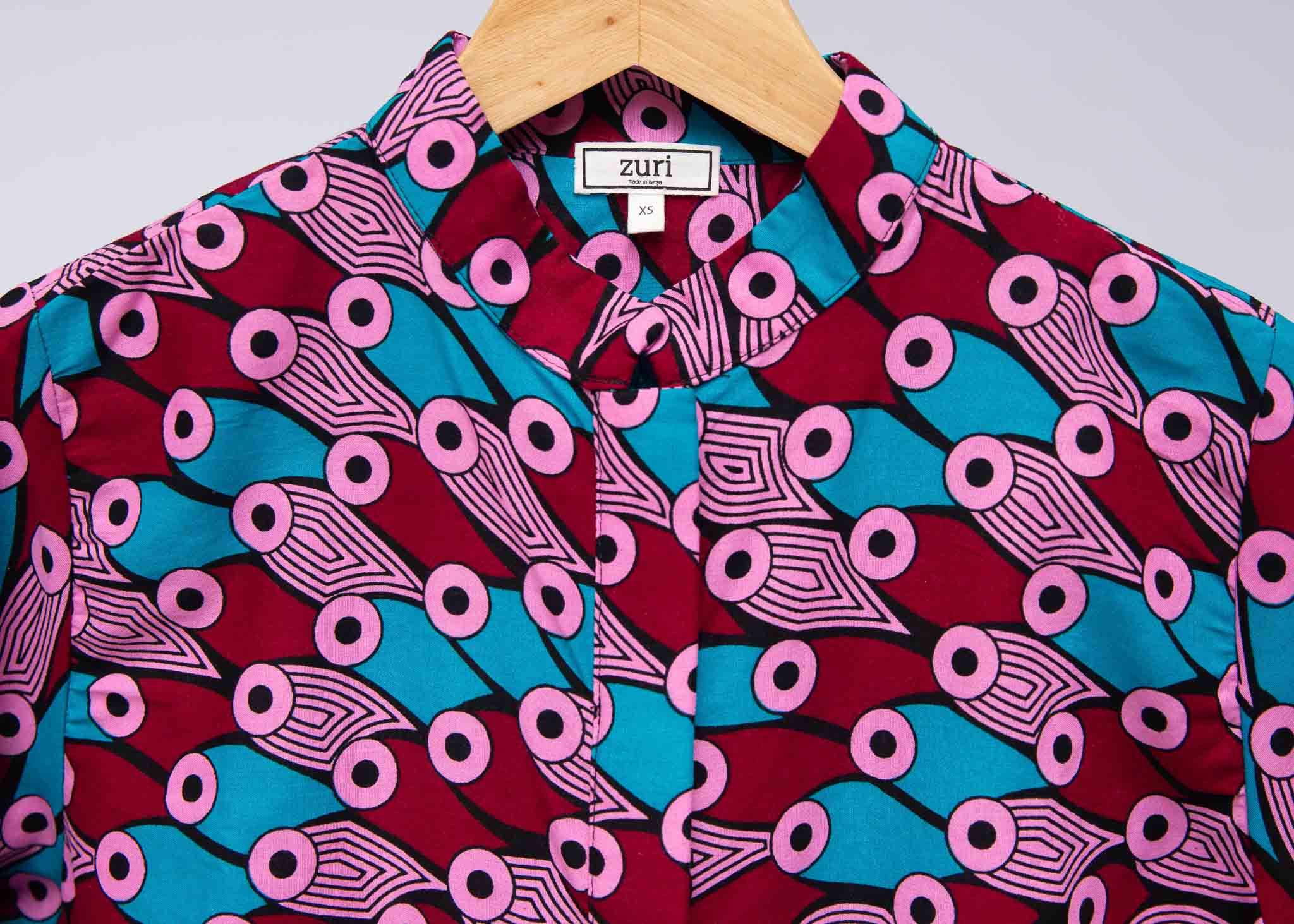 Display of pink, red, blue and black tube print long sleeve blouse.