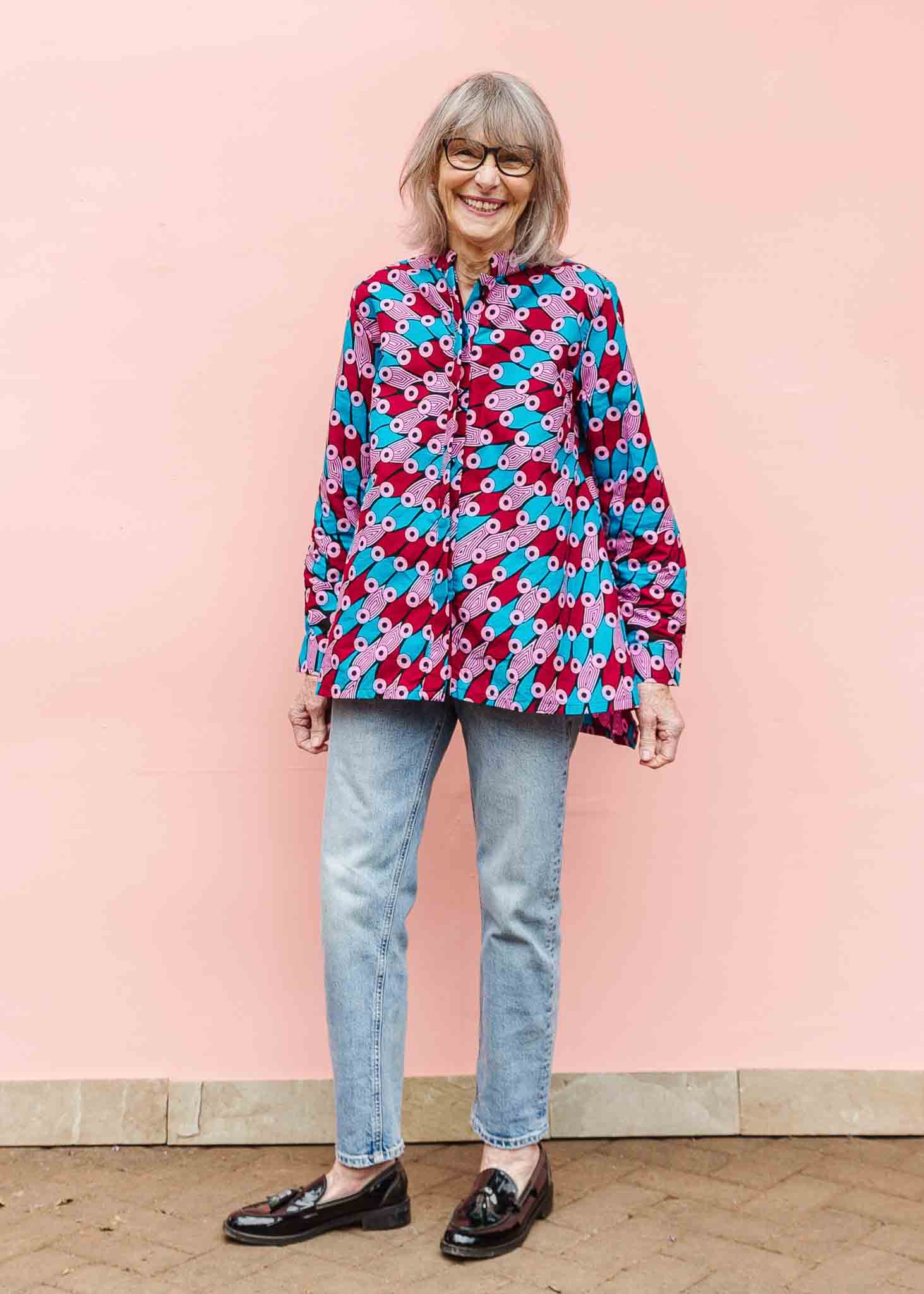 Model wearing pink, red, blue and black tube print long sleeve blouse.