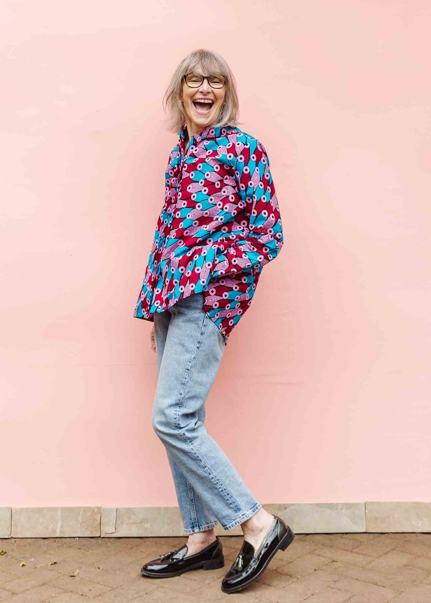 Model wearing pink, red, blue and black tube print long sleeve blouse.