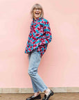 Model wearing pink, red, blue and black tube print long sleeve blouse.