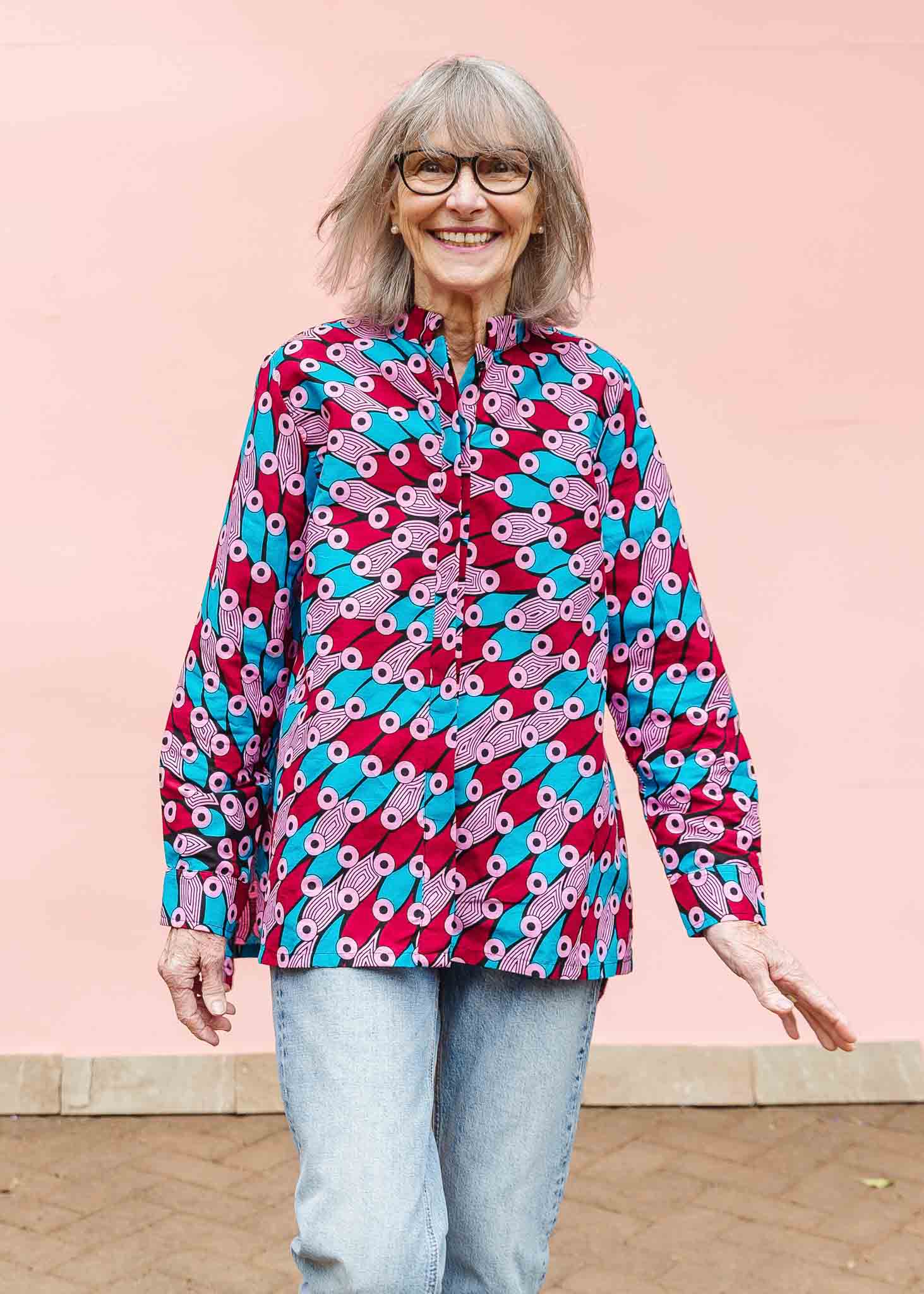Model wearing pink, red, blue and black tube print long sleeve blouse.