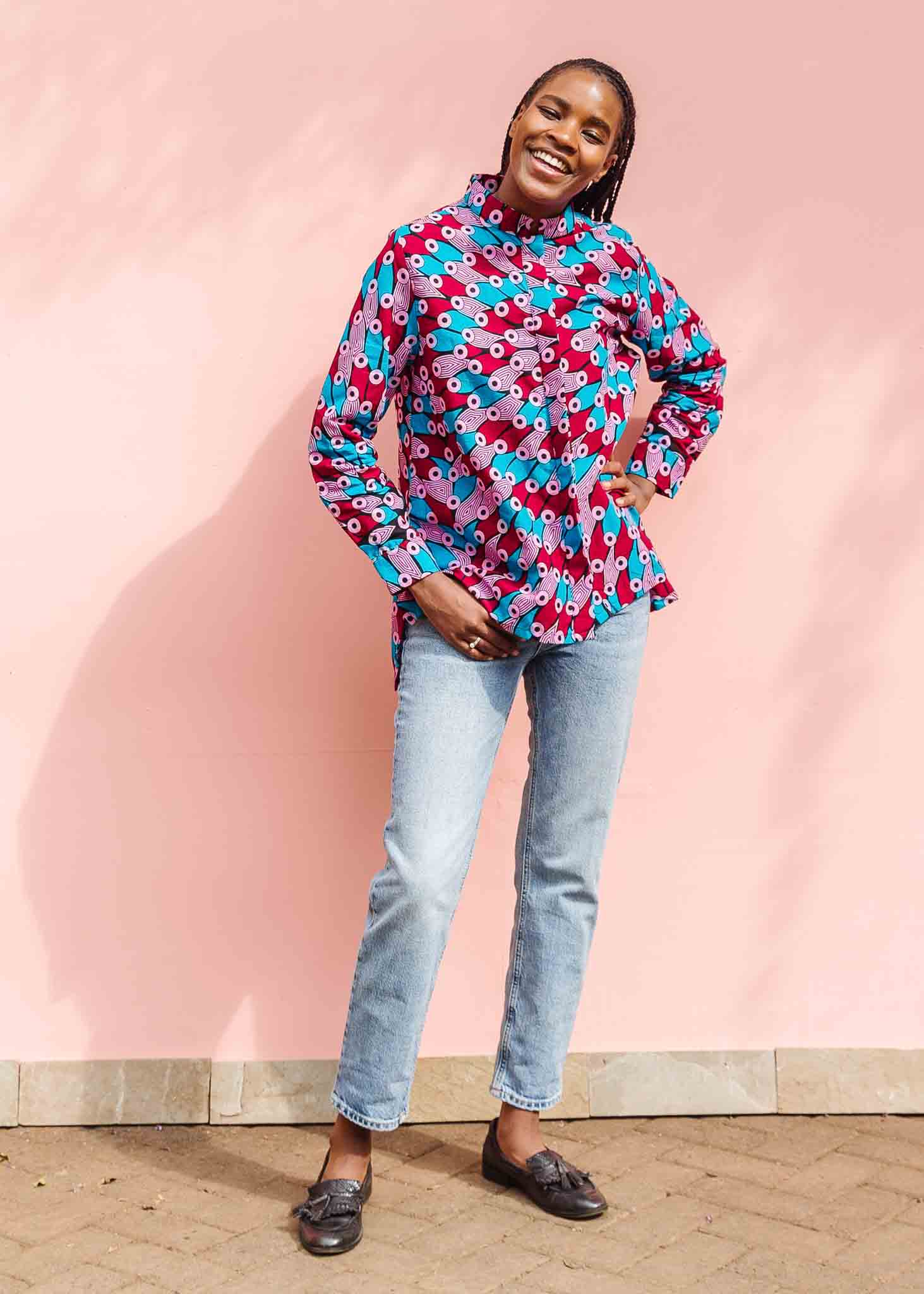 Model wearing pink, red, blue and black tube print long sleeve blouse.