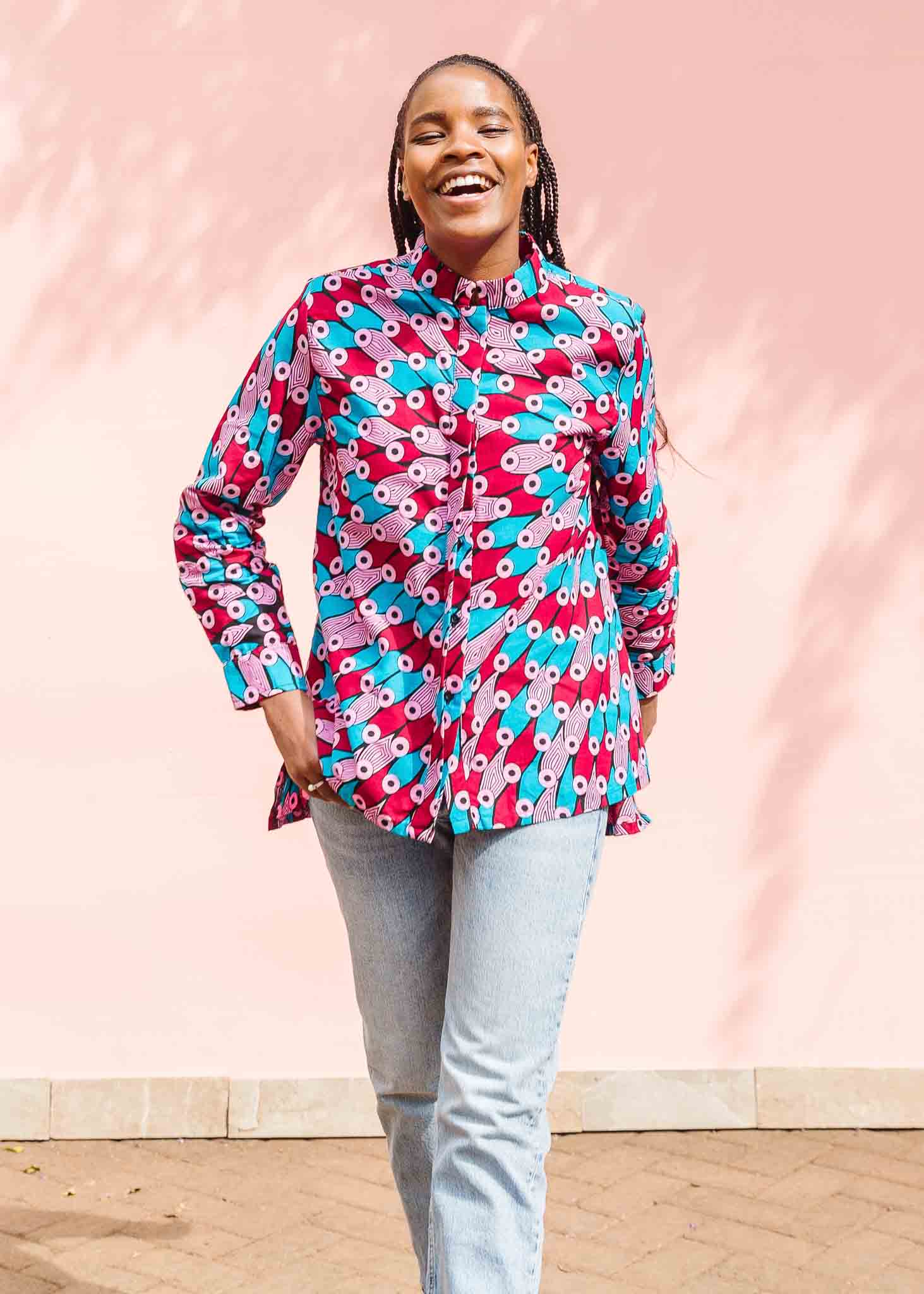 Model wearing pink, red, blue and black tube print long sleeve blouse.