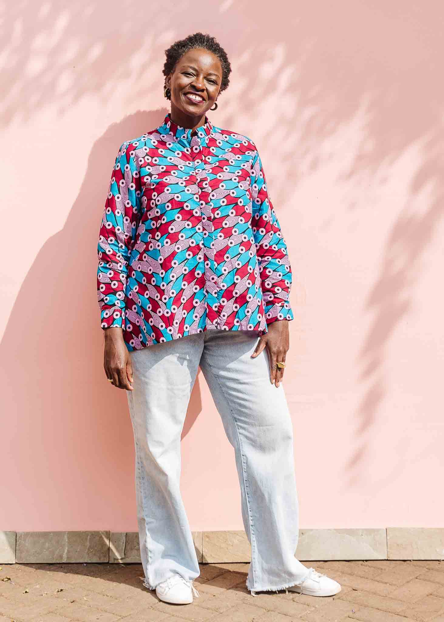 Model wearing pink, red, blue and black tube print long sleeve blouse.