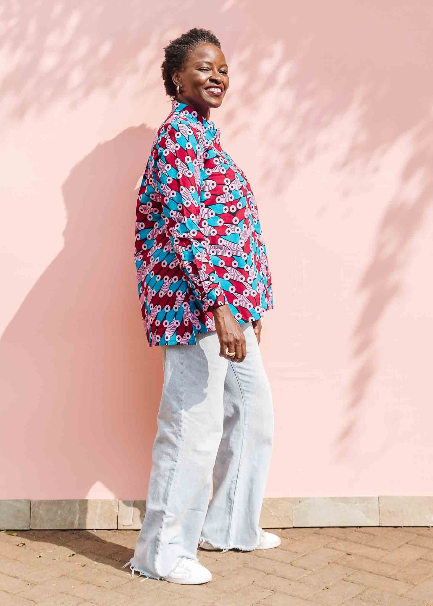 Model wearing pink, red, blue and black tube print long sleeve blouse.