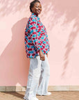 Model wearing pink, red, blue and black tube print long sleeve blouse.