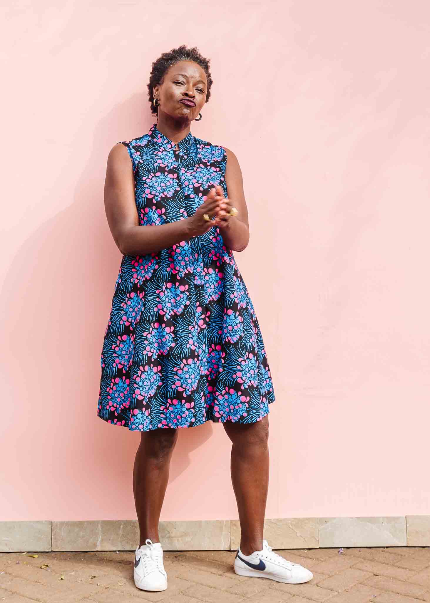 Model wearing black sleeveless dress with blue and pink poppy print.