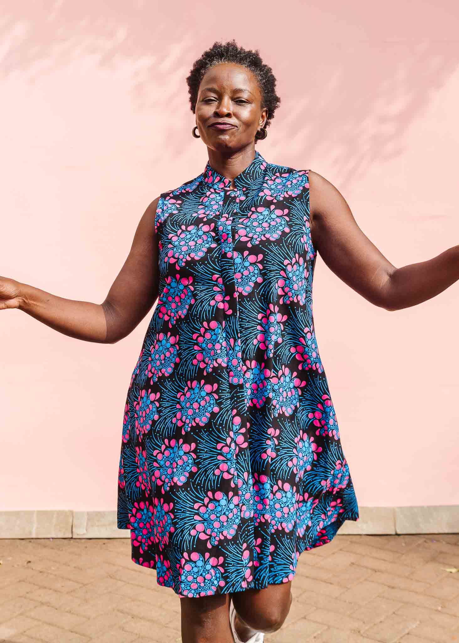 Model wearing black sleeveless dress with blue and pink poppy print.