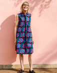 Model wearing black sleeveless dress with blue and pink poppy print.