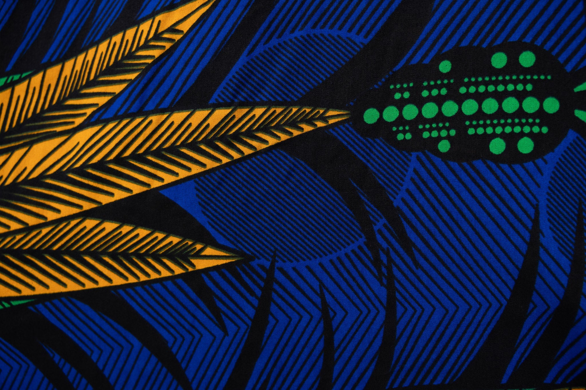 Close up display of blue sleeveless dress with orange and green print.