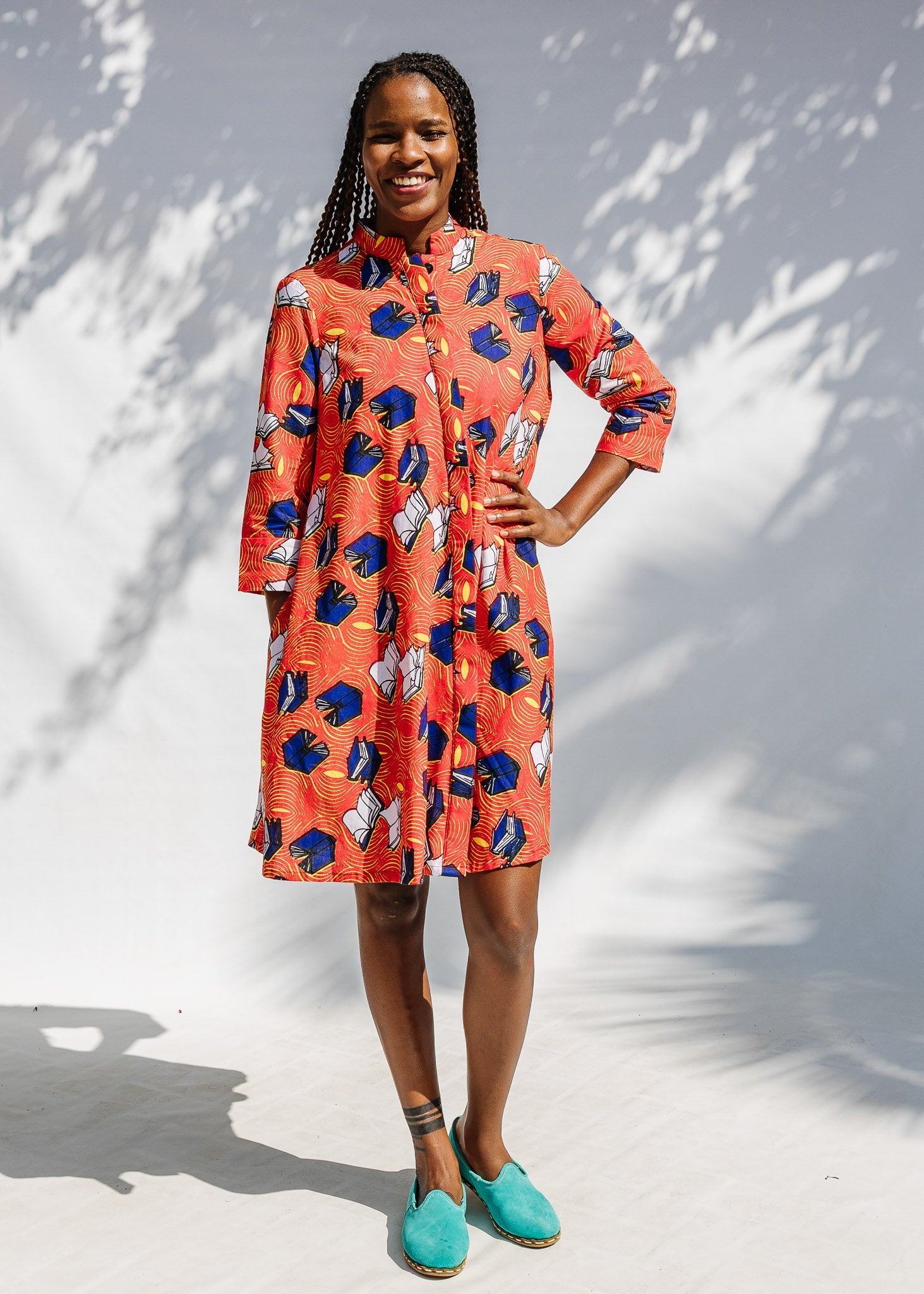 Model wearing yellow and red, blue book print dress.