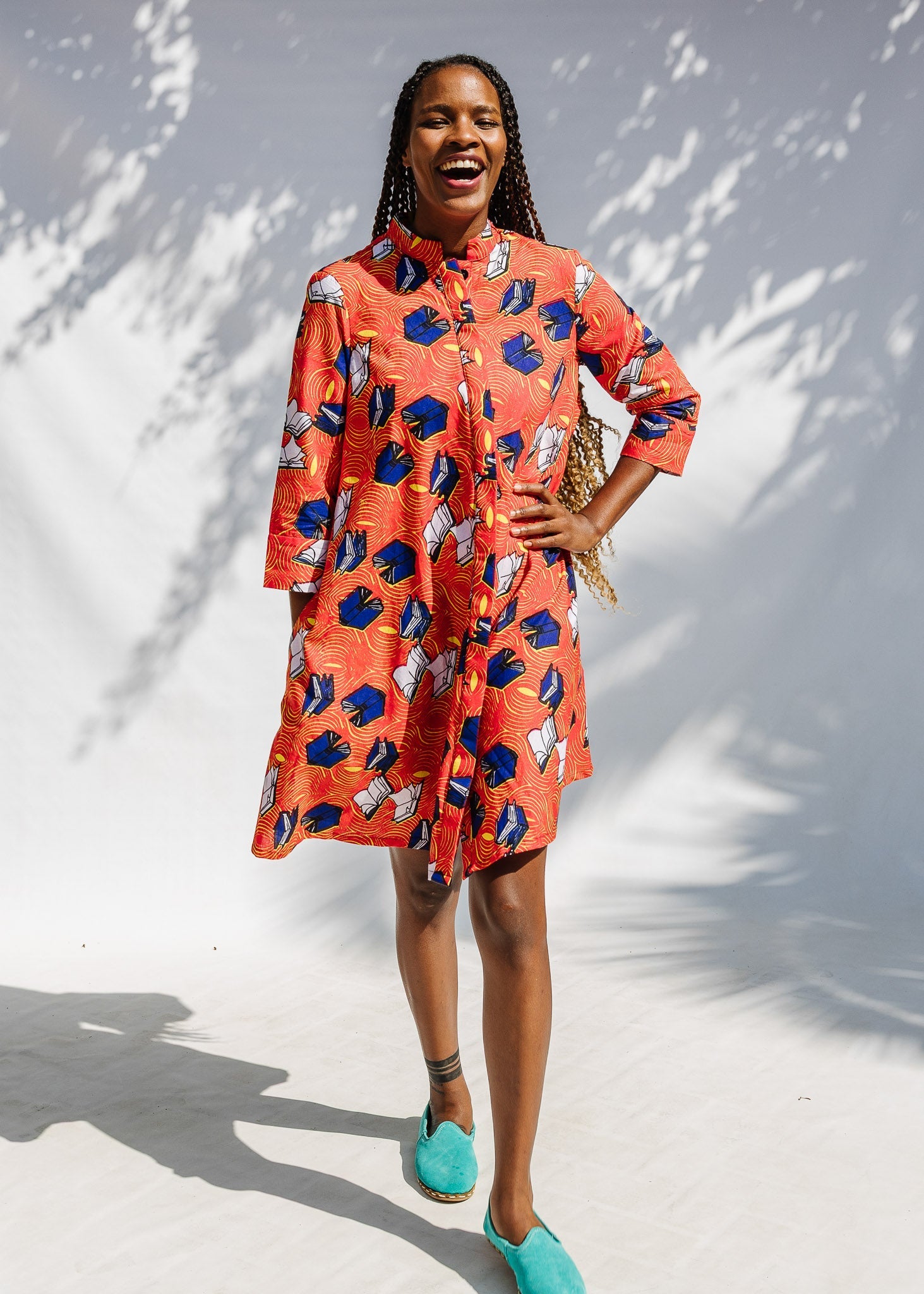 Model wearing yellow and red, blue book print dress.