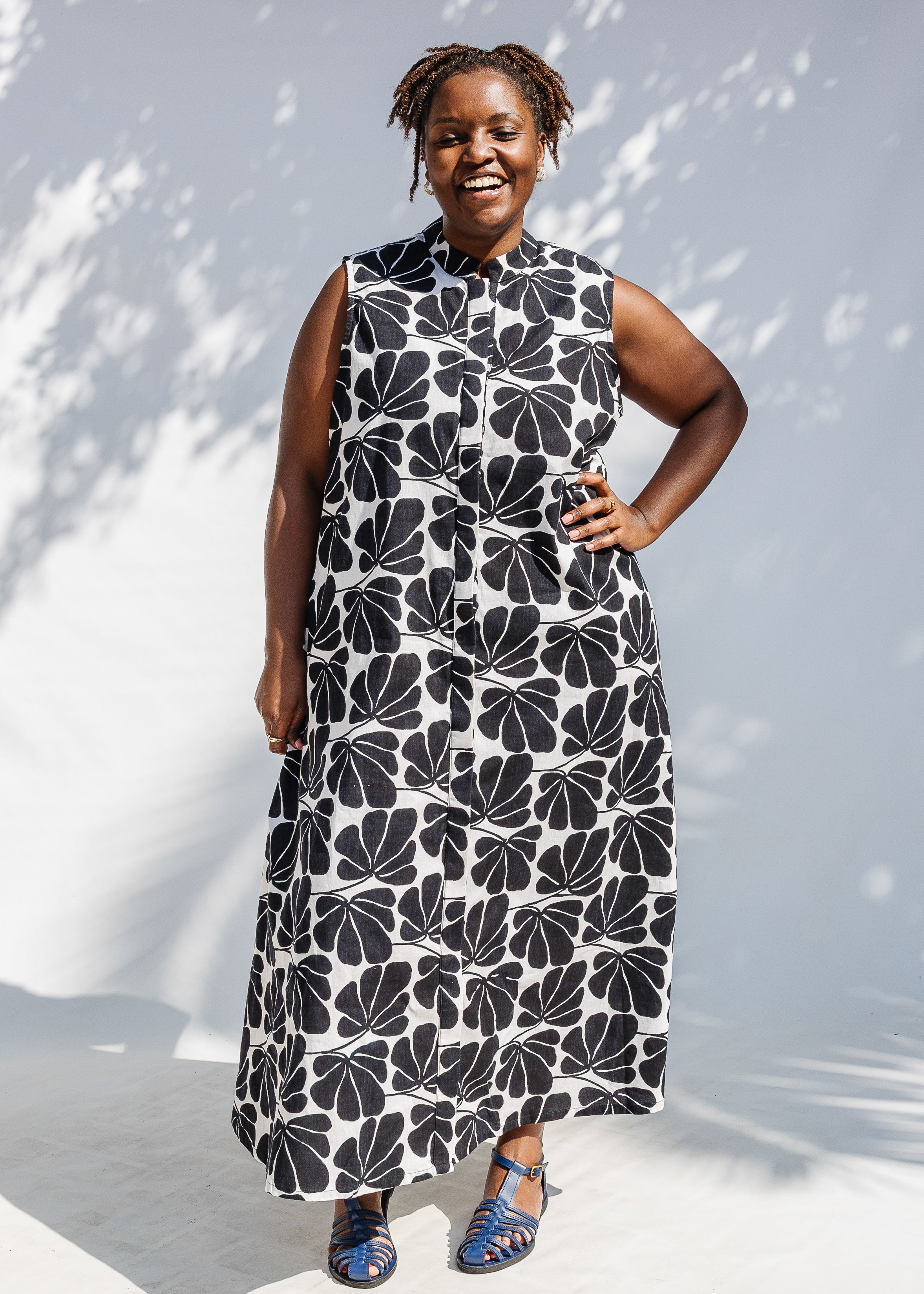 Model wearing black and white floral print, sleeveless dress.