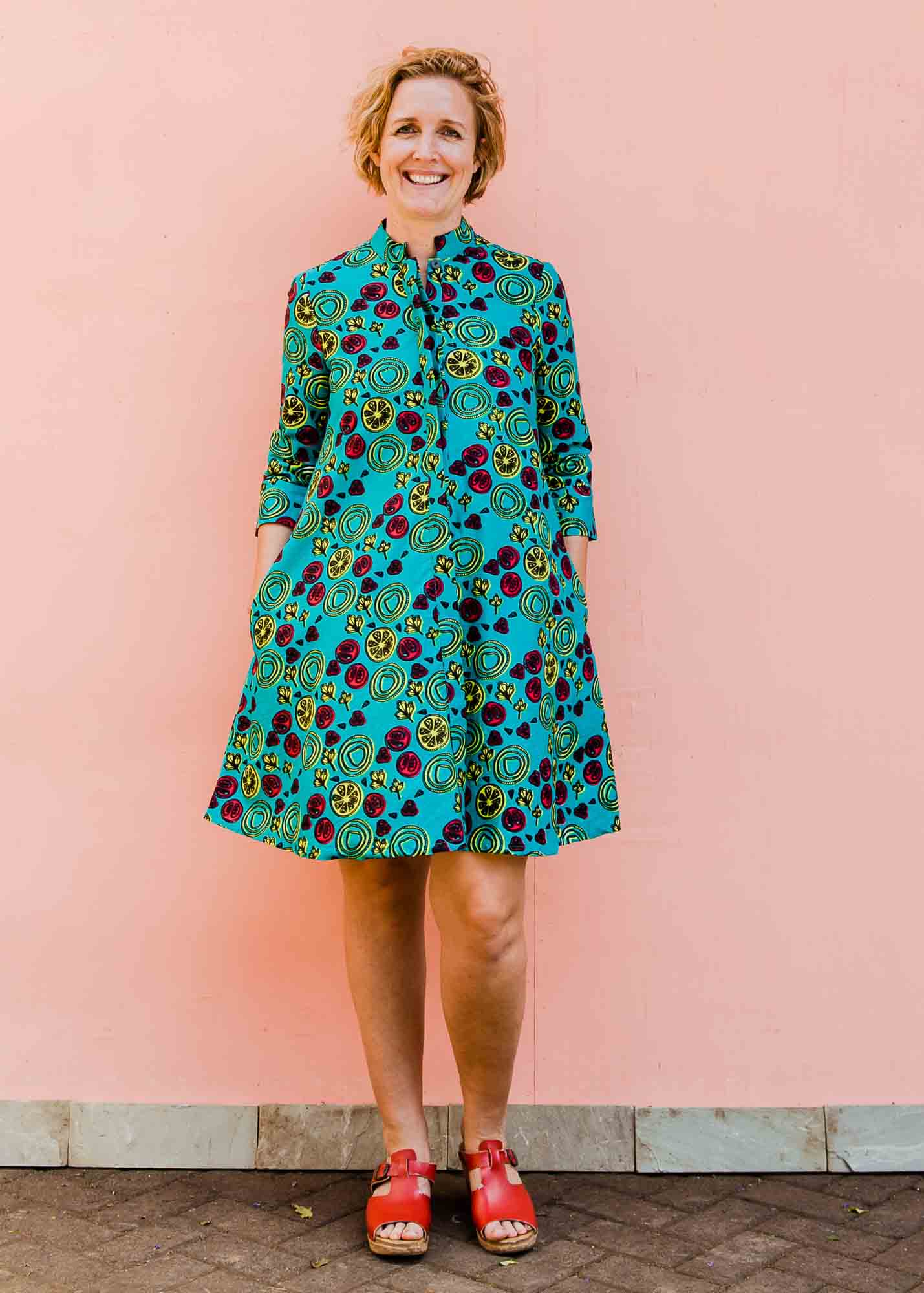 model wearing a green, red and yellow vegetable design dress