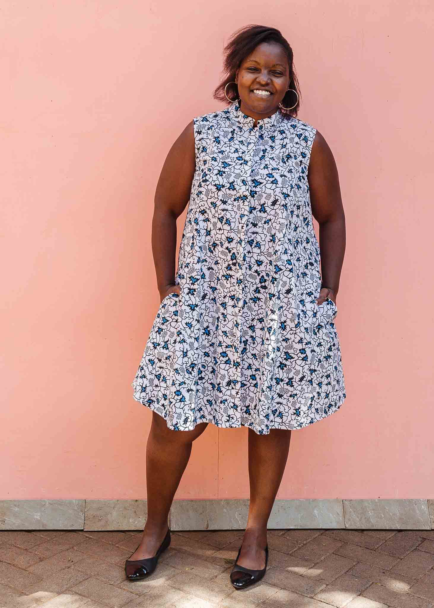 Model wearing white sleeveless dress with blue floral print.