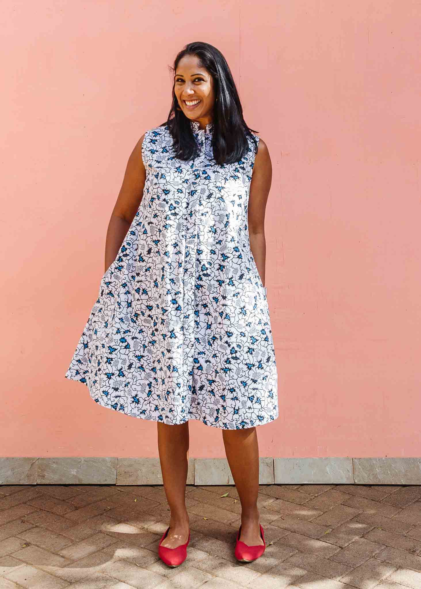 Model wearing white sleeveless dress with blue floral print.