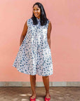 Model wearing white sleeveless dress with blue floral print.