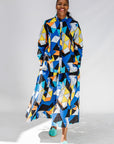 Model wearing blue, black, orange, yellow and white geometric print shirt and pant set.