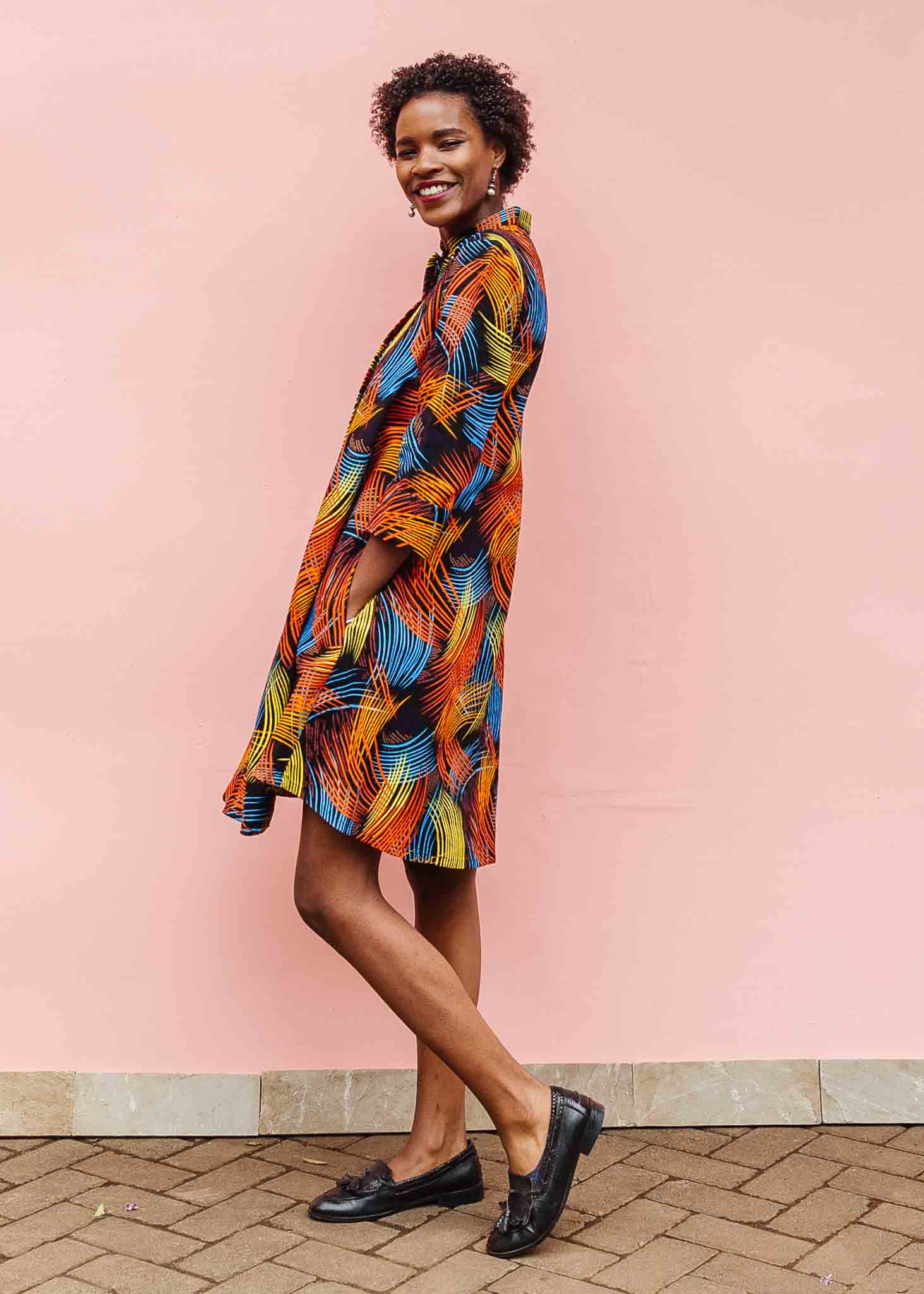 Model wearing black dress with rainbow brushstroke print.