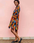 Model wearing black dress with rainbow brushstroke print.