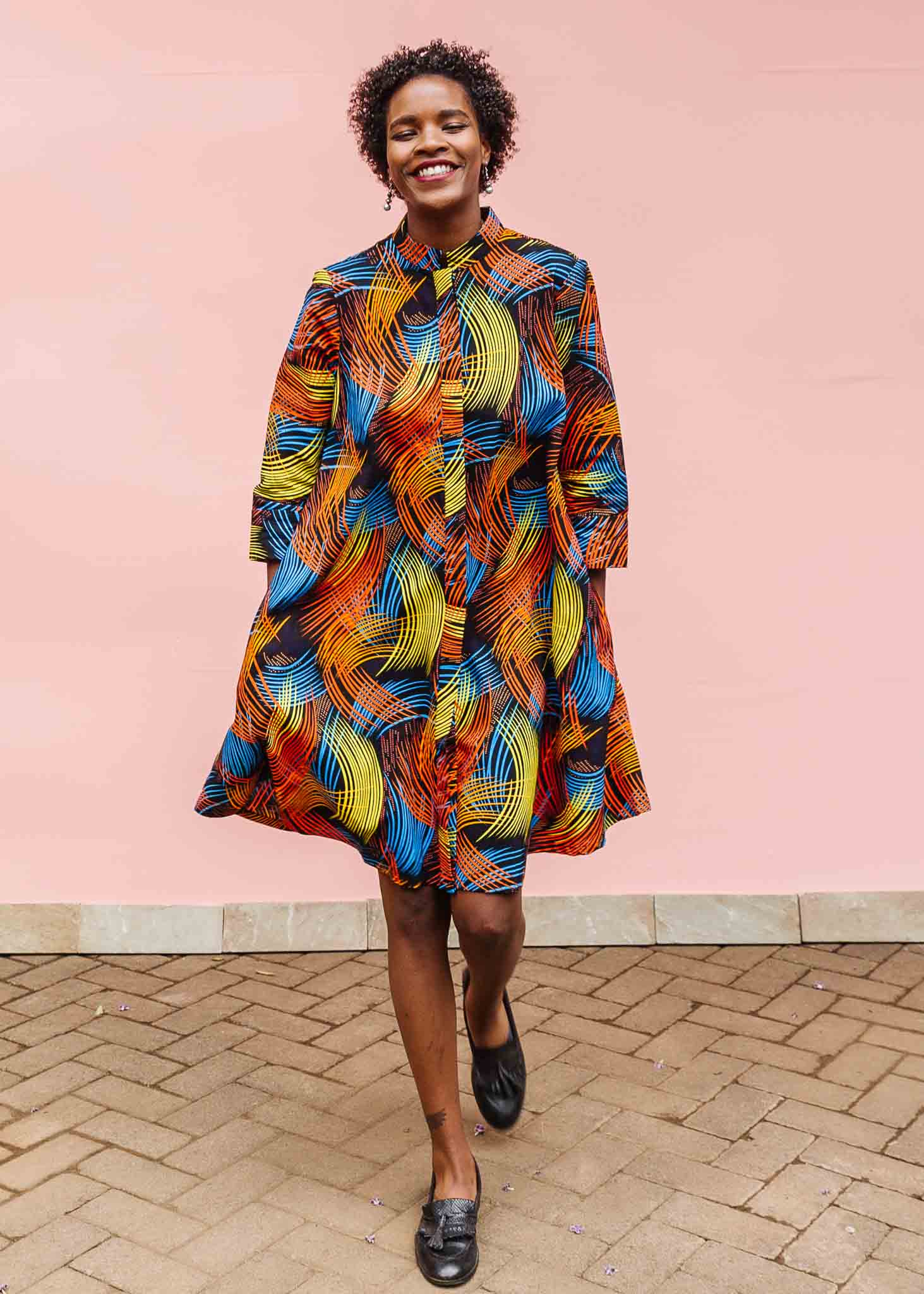 Model wearing black dress with rainbow brushstroke print.