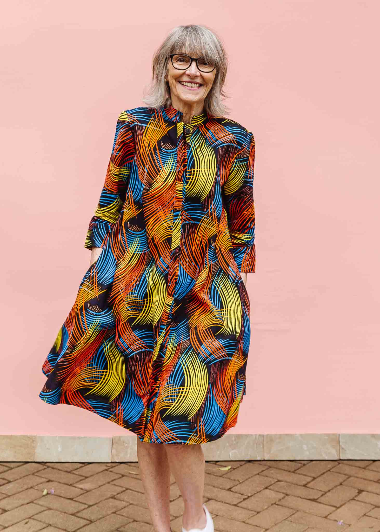 Model wearing black dress with rainbow brushstroke print.