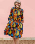 Model wearing black dress with rainbow brushstroke print.