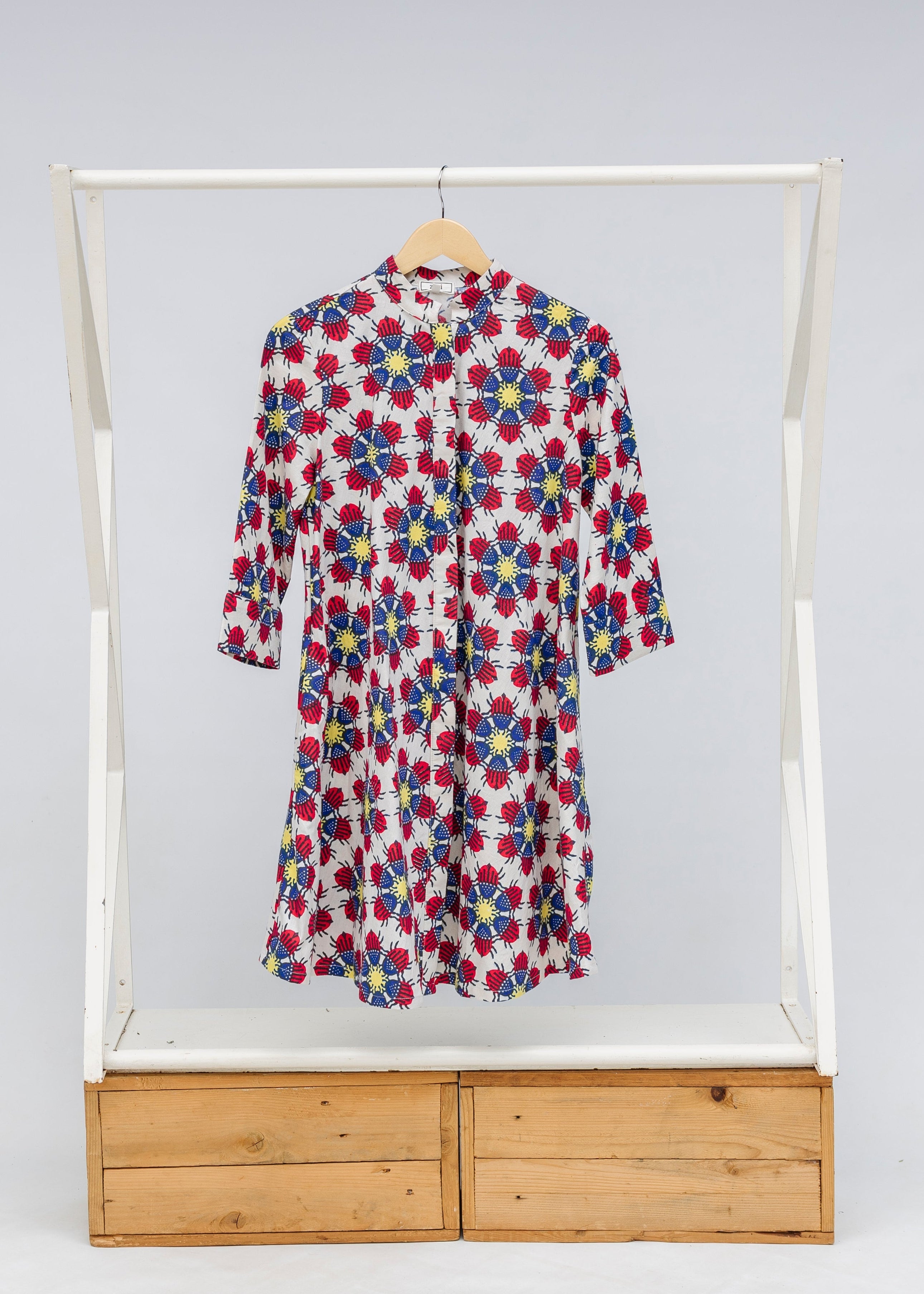 Display of white dress with yellow, red and blue bug print.