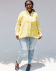 Model wearing yellow long sleeve shirt with white leaf print.