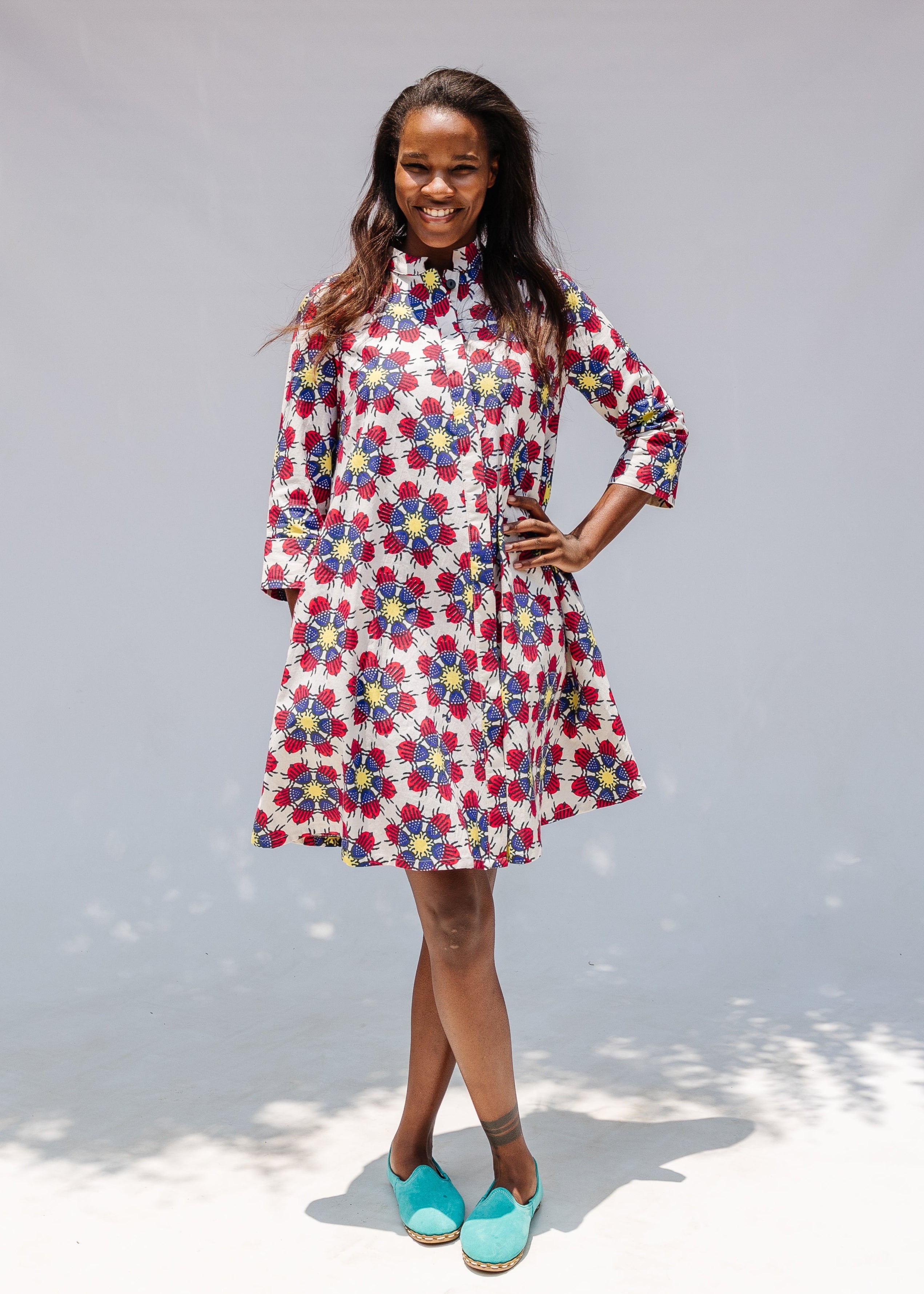 Model wearing white dress with yellow, red and blue bug print.