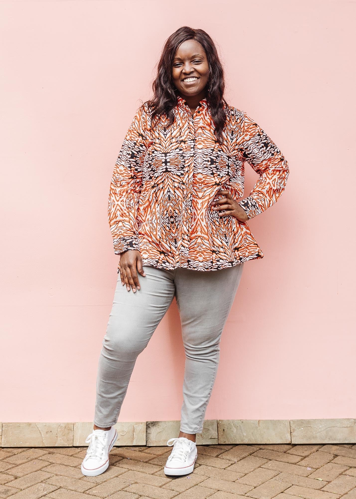 The model is wearing orange, black and white abstract print long sleeved shirt