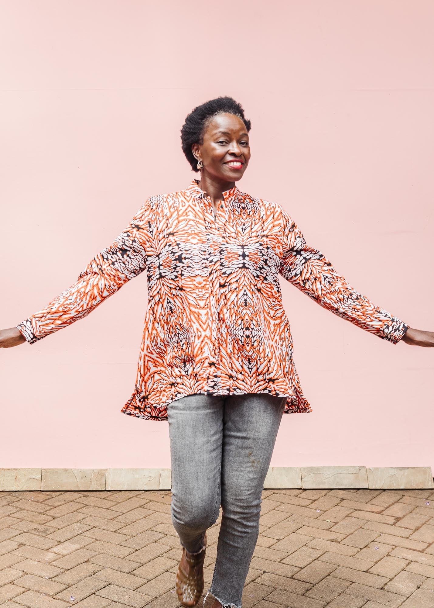 The model is wearing orange, black and white abstract print long sleeved shirt