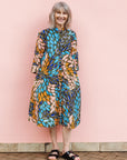 The model is wearing black dress with yellow dots and brown, blues, peach leaves.
