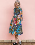The model is wearing black dress with yellow dots and brown, blues, peach leaves.