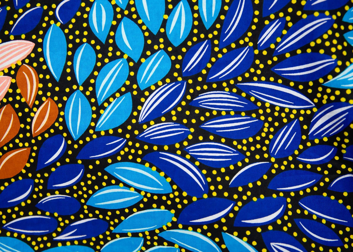 Close up display of black dress with yellow dots and brown, blues, peach leaves.