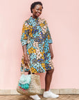 The model is wearing black dress with yellow dots and brown, blues, peach leaves.