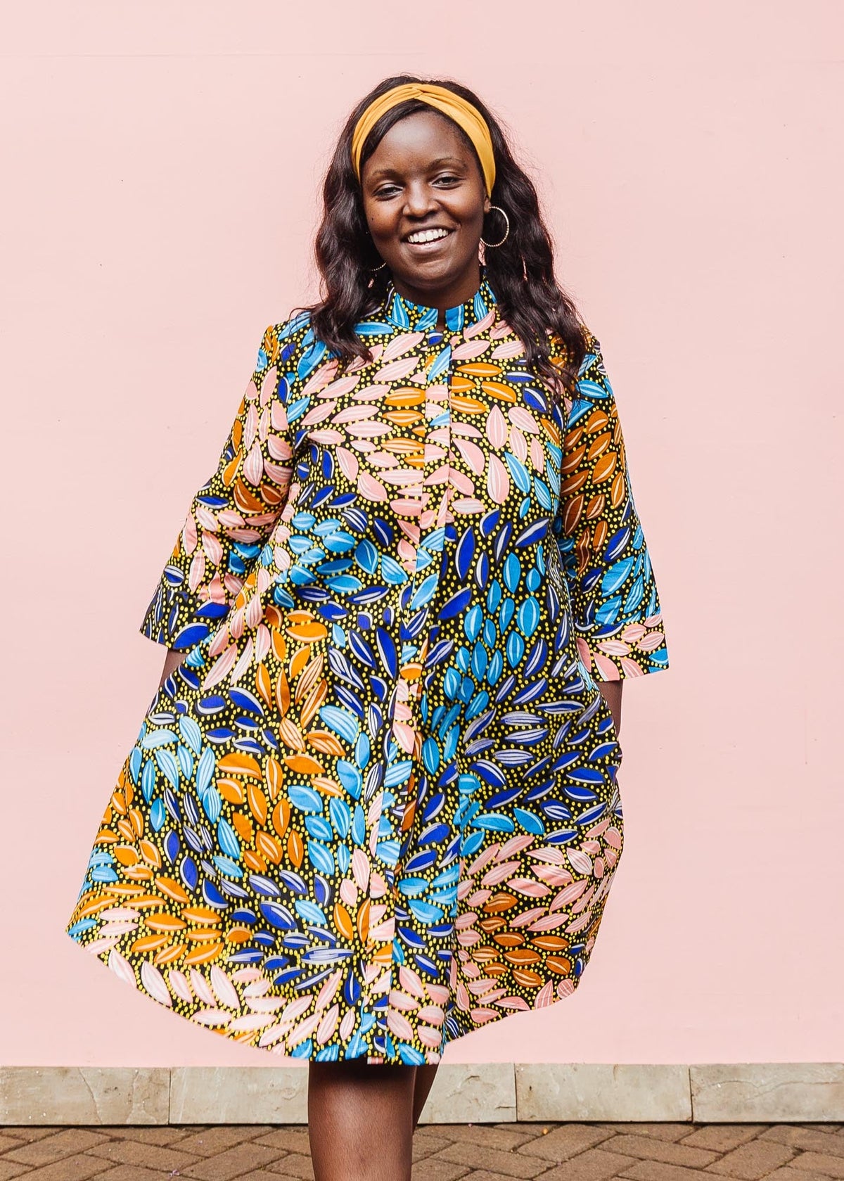 The model is wearing black dress with yellow dots and brown, blues, peach leaves.