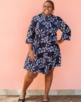 Model wearing navy dress with white floral print.