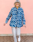 Model wearing blue batik shirt with white domino print, paired with gray jeans and white sneakers.