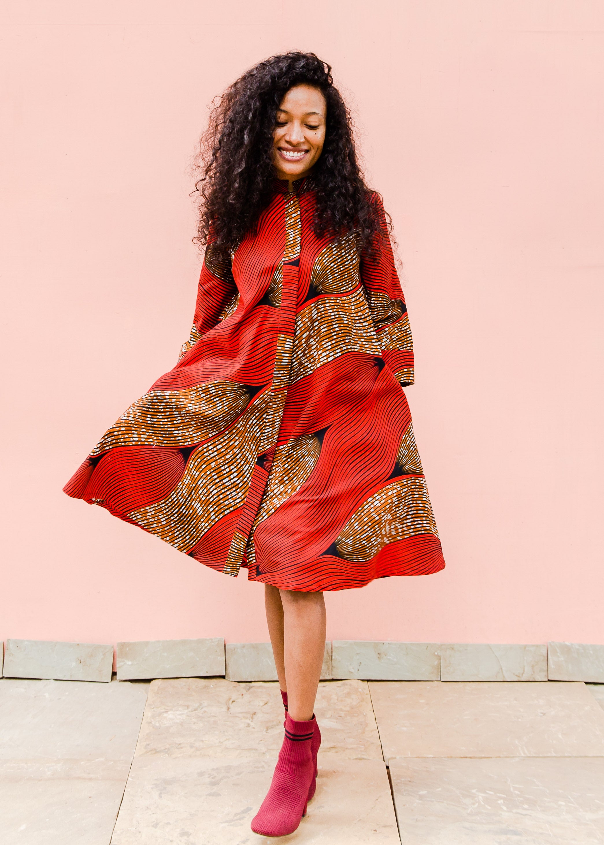 Model wearing red and brown abstract print dress.