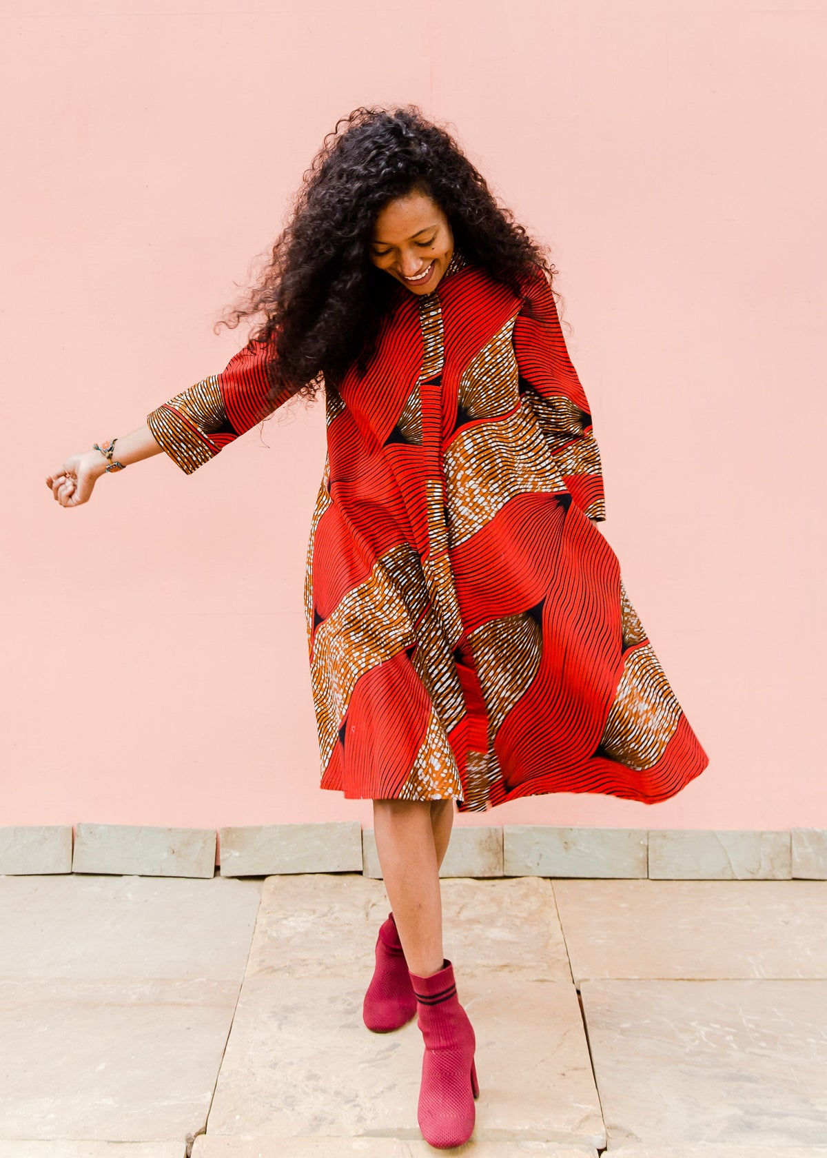 Model wearing red and brown abstract print dress.