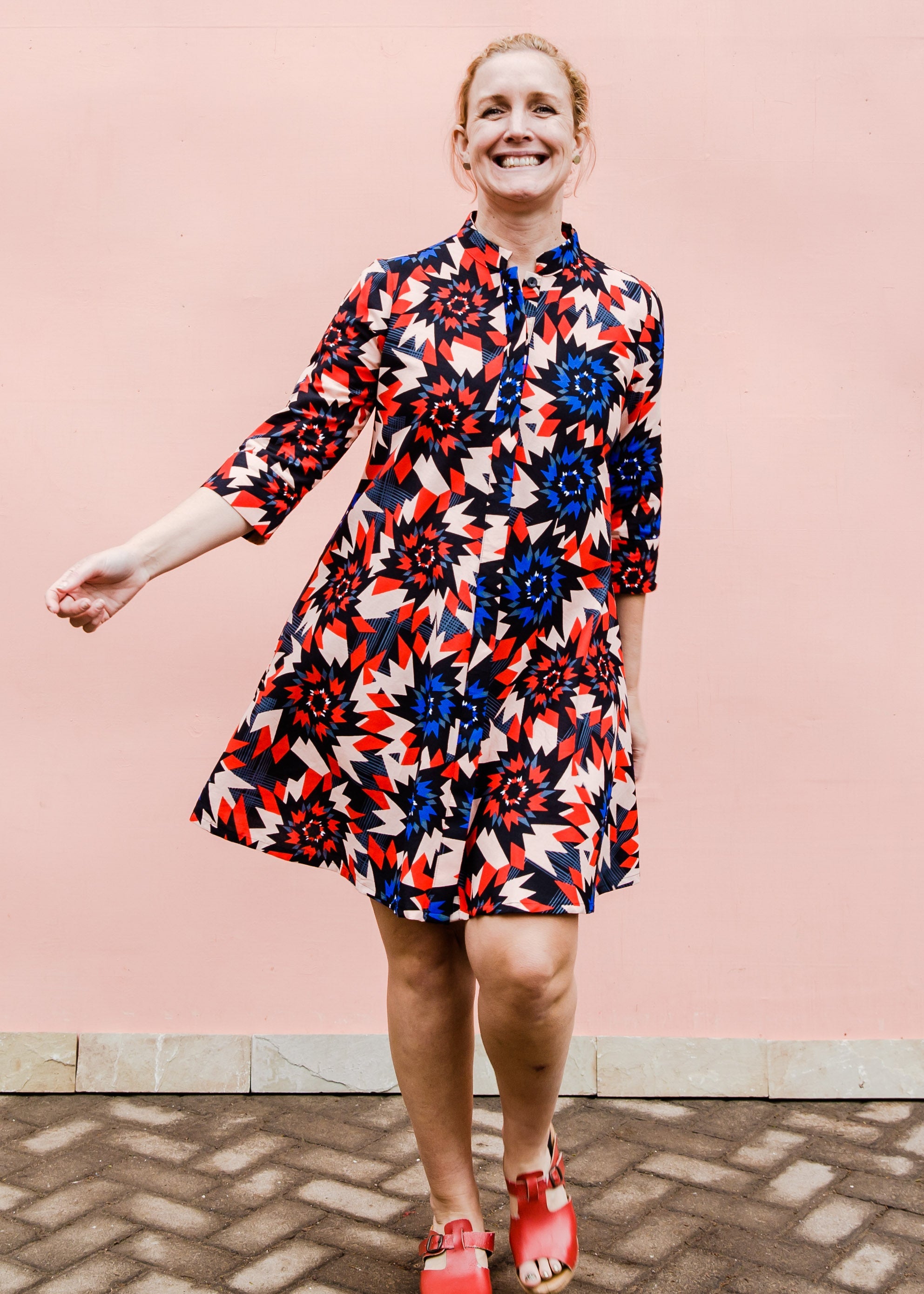 model wearing a colorful geometric shirt dress with a pinwheel design