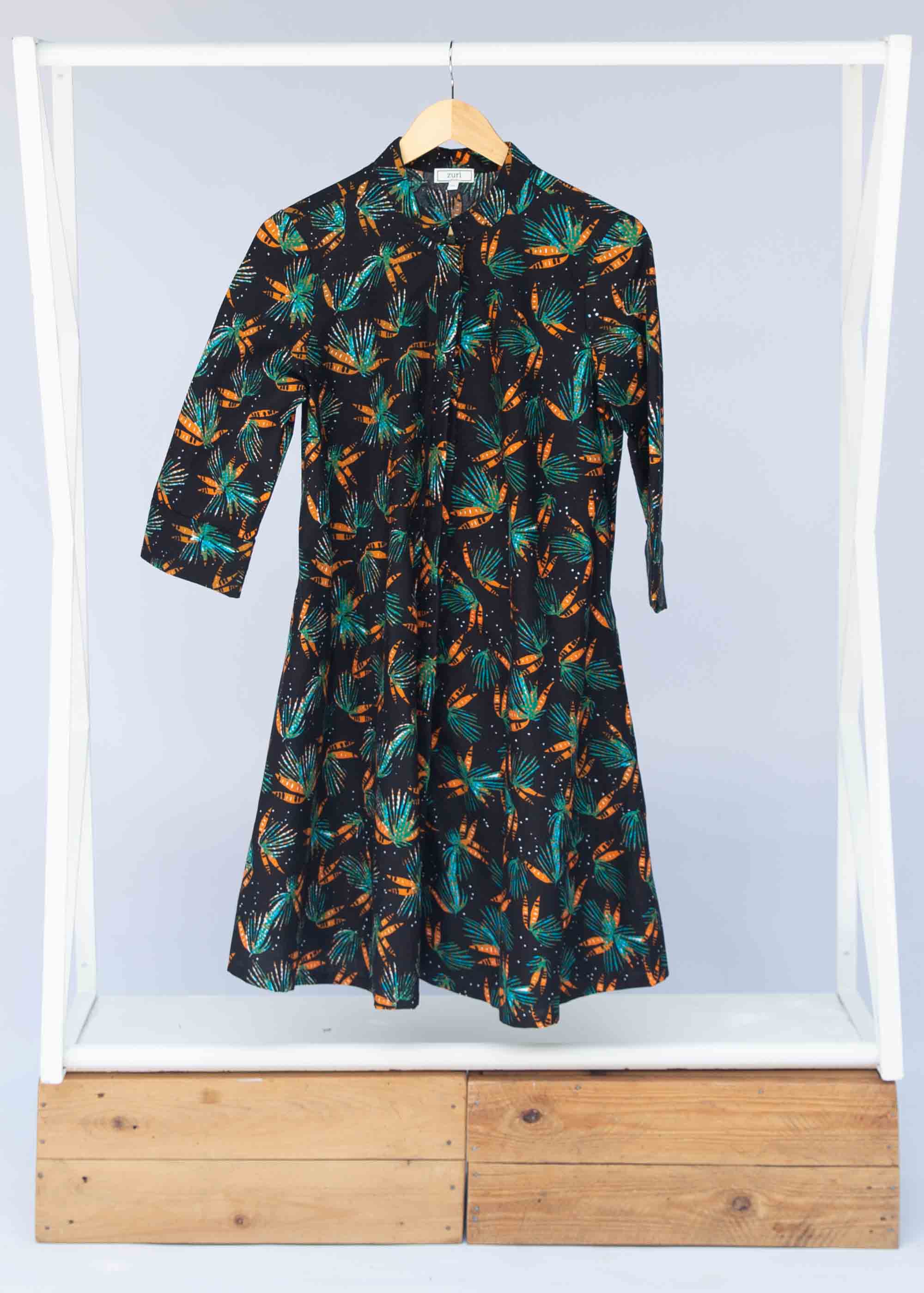 Display of black dress with teal and orange leaves with white dots.