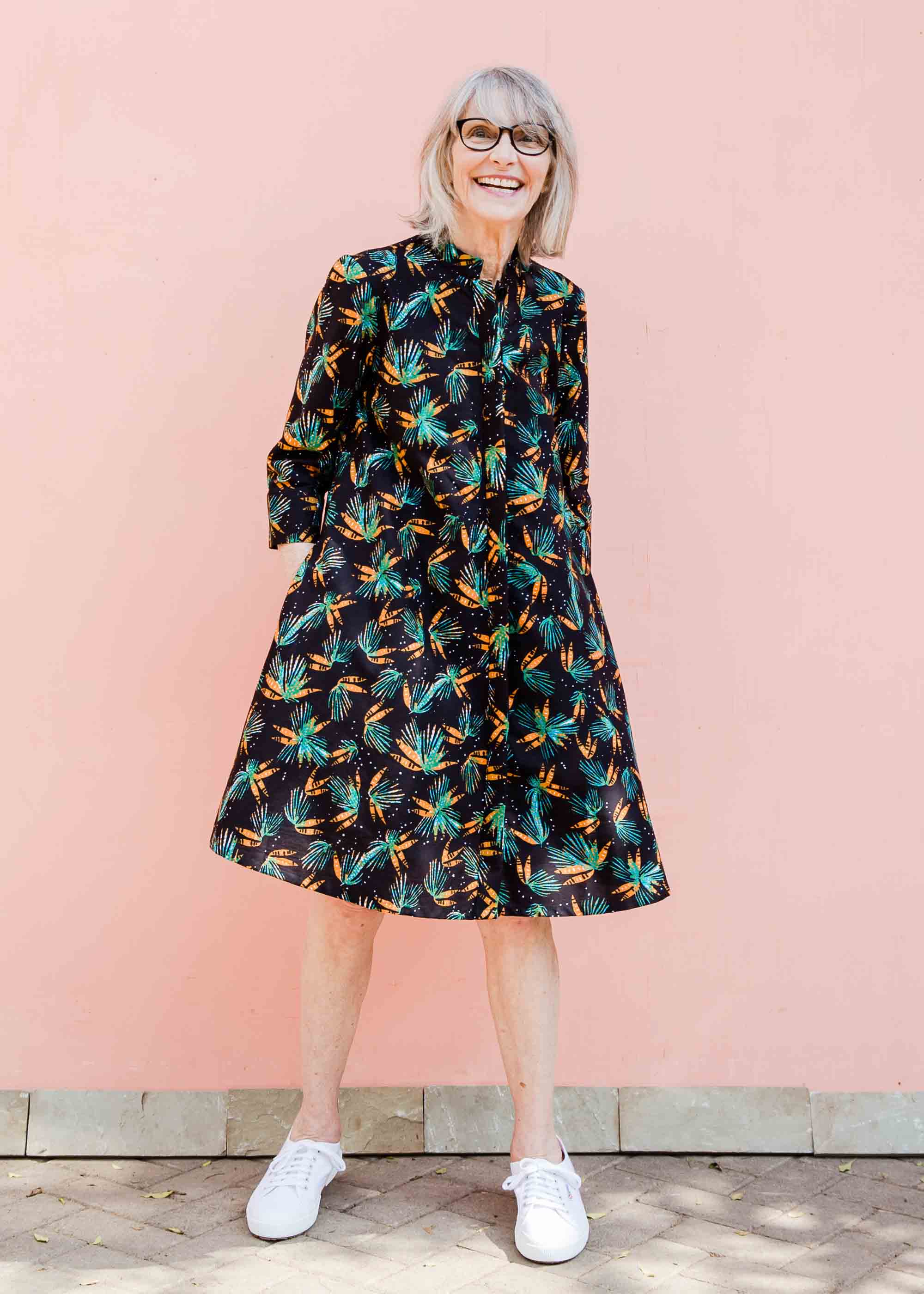 Model wearing black dress with teal and orange leaves with white dots